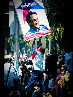 Homem tentando retirar o cartaz eleitoral de Piñera durante o enterro de Victor Jara que foi assassinado durante a ditadura de Pinochet. Foto tirada pelo usuário do Flickr Amable Odiable e usada sob licença da Creative Commons.