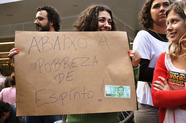 A protester holds a post saying "Down with the poverty of spirit!". Photo by Fernando Baldan, on Flickr. Published with permission.