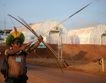 Indigenous wields bow and arrow in front of the construction site. © Ivan Canabrava/ Illuminati filmes shared by Xingu Vivo (used with permission)