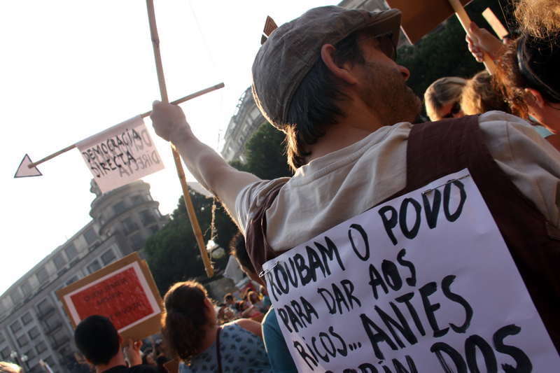 "Κλέβουν τον κόσμο για να δώσουν στους πλούσιους...προτιμώ τον Robin Hood. Άμεση Δημοκρατία". Παγκόσμια επανάσταση για αληθινή Δημοκρατία στο Πόρτο (15/10/2011). Φώτο:Pedro Ferreira, copyright Demotix. 