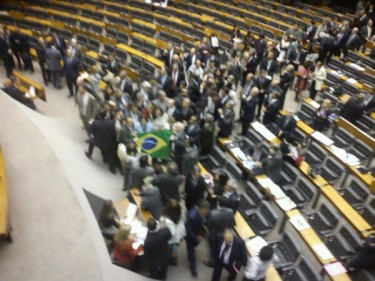 Deputados comemoram e cantam o hino nacional com a bandeira brasileira. Foto de Thiago Skárnio sob licença CC