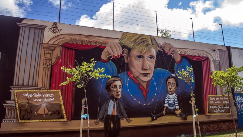 Graffiti with German chancellor Angela Merkel as a puppet master, holding the Portuguese Prime Minister and the Deputy Minister.